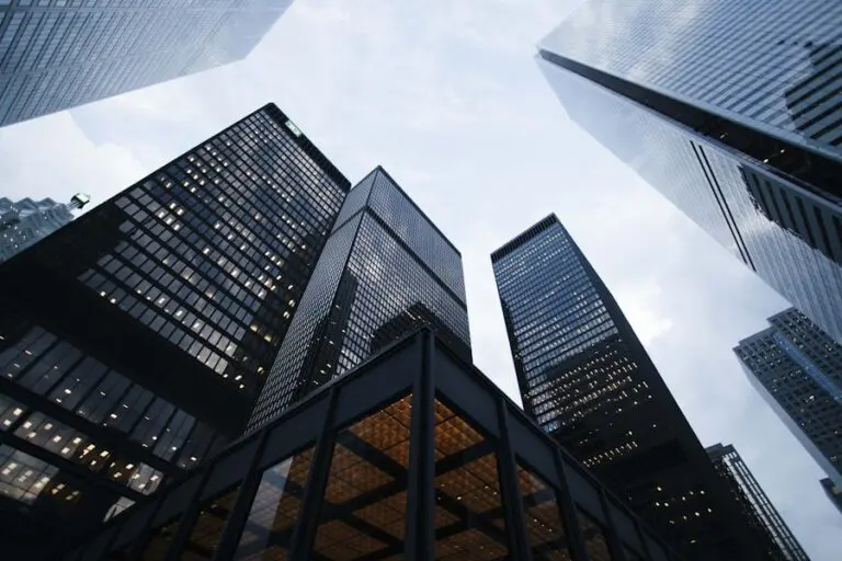 Looking up at tall skyscrapers against a cloudy sky. The buildings are mostly glass and steel, creating a modern and imposing cityscape.